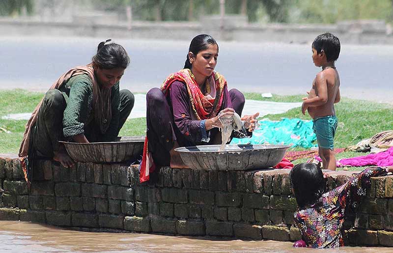 Gypsy ladies washing clothes while sitting on the edge of Canal