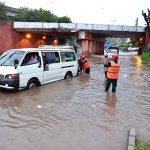 Rescue worker pushing an out of order vehicle which stuck in water accumulated on road due to torrential rain since last night