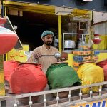A vendor sells traditional summer drink to customers at his roadside setup during hot weather in Provincial Capital