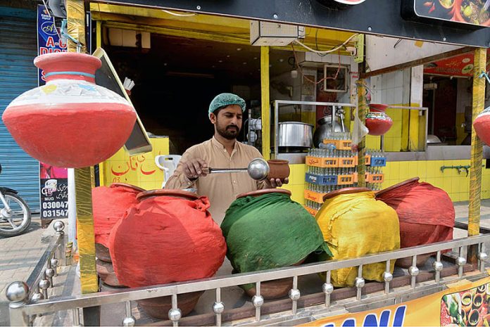 A vendor sells traditional summer drink to customers at his roadside setup during hot weather in Provincial Capital