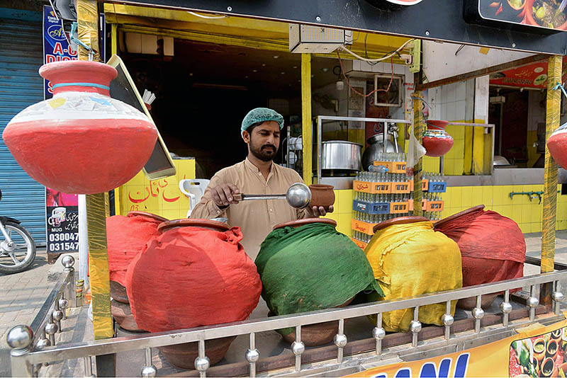 A vendor sells traditional summer drink to customers at his roadside setup during hot weather in Provincial Capital
