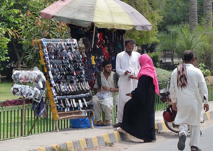 A lady selecting and purchasing sunglasses from a roadside vendor