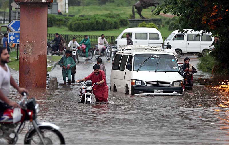 Rescue worker pushing an out of order vehicle which stuck in water accumulated on road due to torrential rain since last night