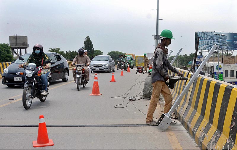 Labourer busy installing iron bars on the roadside divider of Kalma Chowk Flyover to protect from any mishap