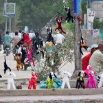 A vendor is displaying the toys to attract the customers on the footpath at Latifabad