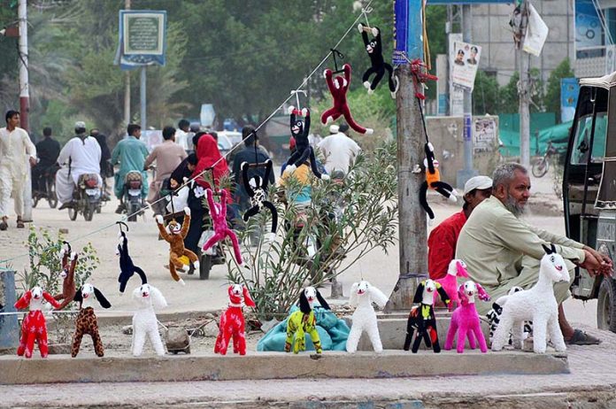 A vendor is displaying the toys to attract the customers on the footpath at Latifabad