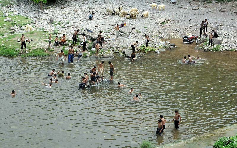 Youngsters jumping and bathing in water channel of Rawal Dam to get some relief from hot weather in Federal Capital