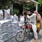 A motorcyclist purchasing flour bag from a roadside stall