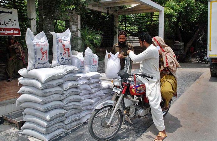 A motorcyclist purchasing flour bag from a roadside stall