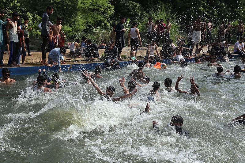 A large number of youngsters enjoy bathing in the local swimming pool at Khisana Mori to get relief from scorching hot weather in the city