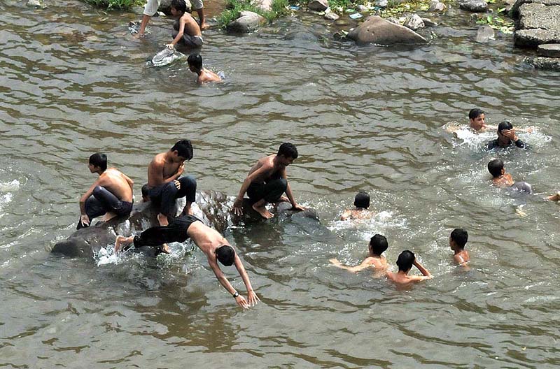 Youngsters jumping and bathing in water channel of Rawal Dam to get some relief from hot weather in Federal Capital
