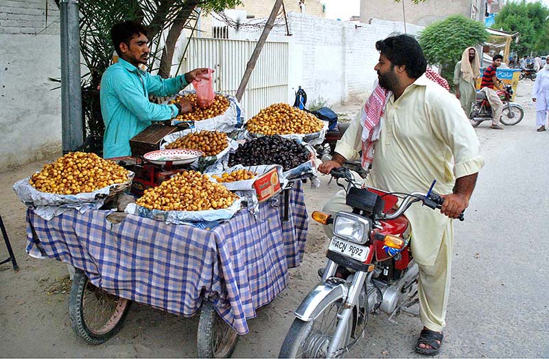 Vendors displaying the seasonal fruit (Dates) to attract the customers at his roadside setup