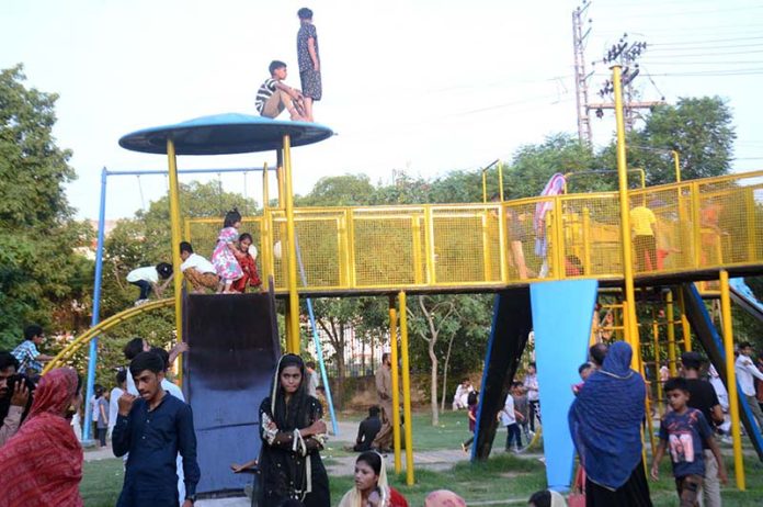 Children enjoying swings with their family members in Bagh e Jinnah