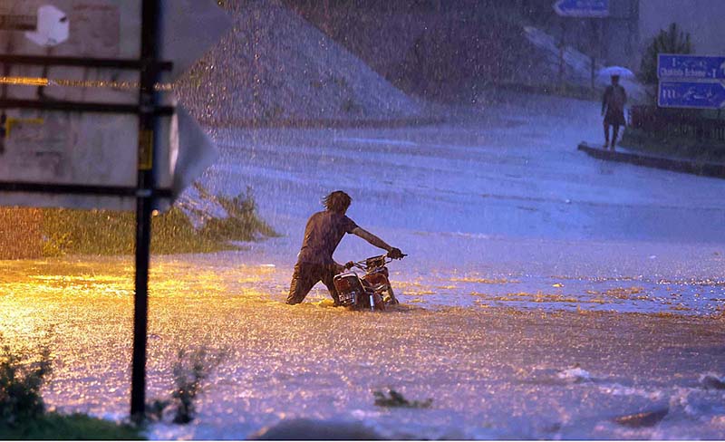 Rescue worker pushing an out of order vehicle which stuck in water accumulated on road due to torrential rain since last night