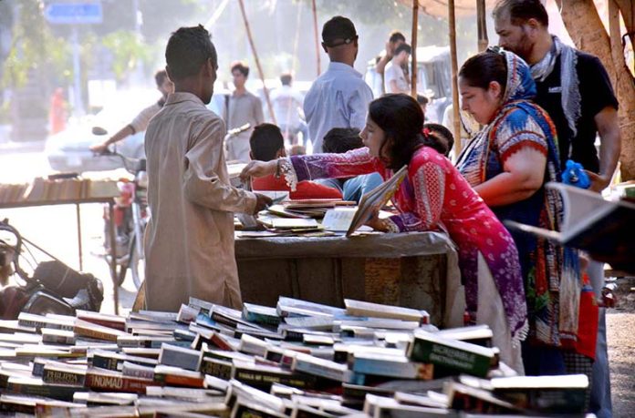 Book lovers selecting old books on a roadside stall in the city