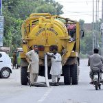 WASA workers busy in cleaning sewerage manhole with help of a machine