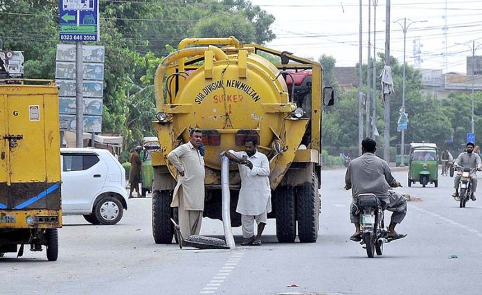 WASA workers busy in cleaning sewerage manhole with help of a machine