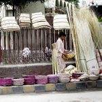 A vendor along with his son busy arranging and displaying bread trays and other domestic-use items to attract customers at his roadside setup