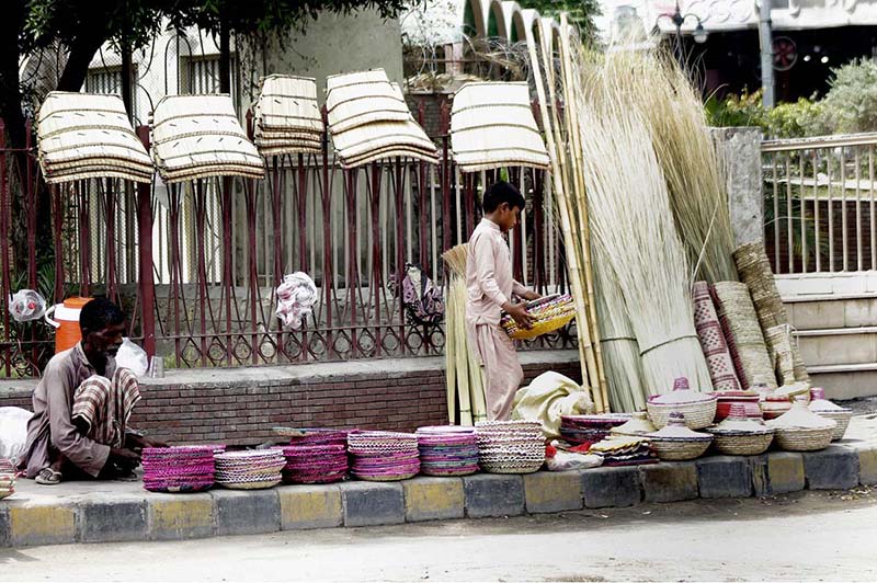 A vendor along with his son busy arranging and displaying bread trays and other domestic-use items to attract customers at his roadside setup