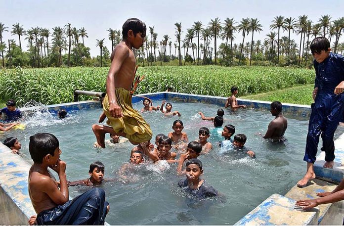 Youngsters bathing in a pond of tube well to get relief from scorching hot weather in the city