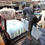 A labourer loading ice block on Suzuki for delivery at Mumtaz Colony