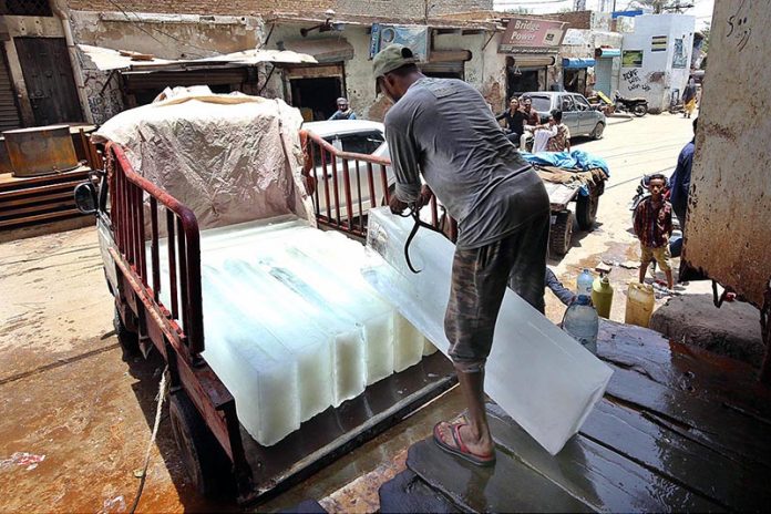 A labourer loading ice block on Suzuki for delivery at Mumtaz Colony