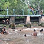 People are swimming in Pinyari Canal to get relief from hot and humid weather in the city