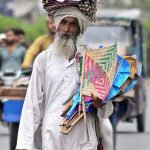 An elder vendor selling traditional handmade fans while shuttling on Masoom Shah Road