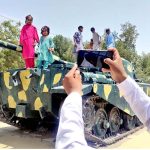 A man takes a picture of his children by his mobile phone on the 2nd day of Eid Ul Azha at Tank Chowk near Railway Station
