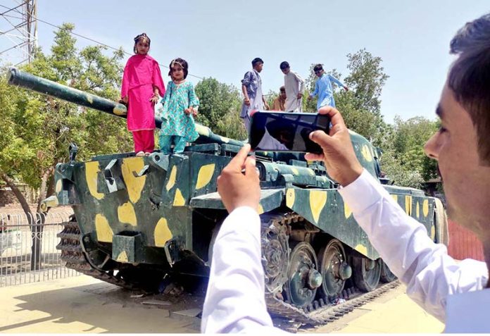 A man takes a picture of his children by his mobile phone on the 2nd day of Eid Ul Azha at Tank Chowk near Railway Station