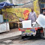 A labourer busy in unloading ice blocks from a delivery van at his roadside setup as demand increased during hot weather
