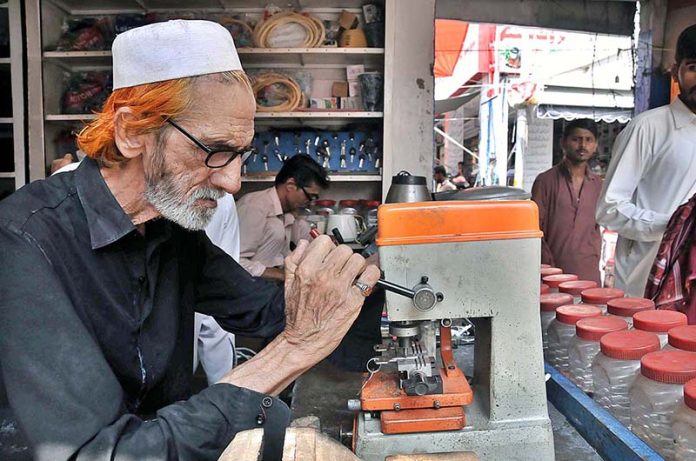An elderly person busy in making duplicate key at Aabpara Market