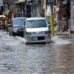 Vehicles passing through rain water accumulated on road after rain that experienced the city