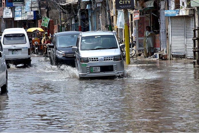 Vehicles passing through rain water accumulated on road after rain that experienced the city Vehicles passing through rain water accumulated on road after rain that experienced the city