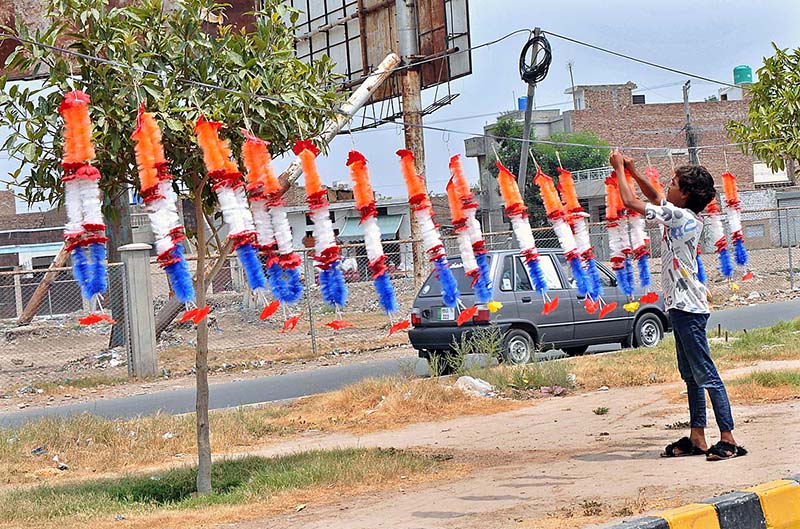 A young vendor arranging and displaying garlands to attract the customers at Airport Road