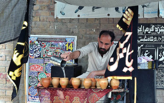 Volunteer serving Sabeel during the 06th Muharram Ul Haram procession at Shah Shams