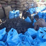Vendors packing coal bags for displaying to attract customers at his workplace near Haji Camp