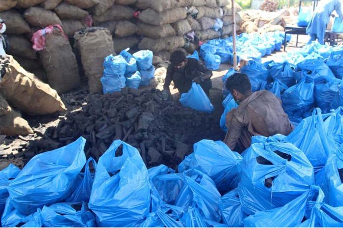 Vendors packing coal bags for displaying to attract customers at his workplace near Haji Camp