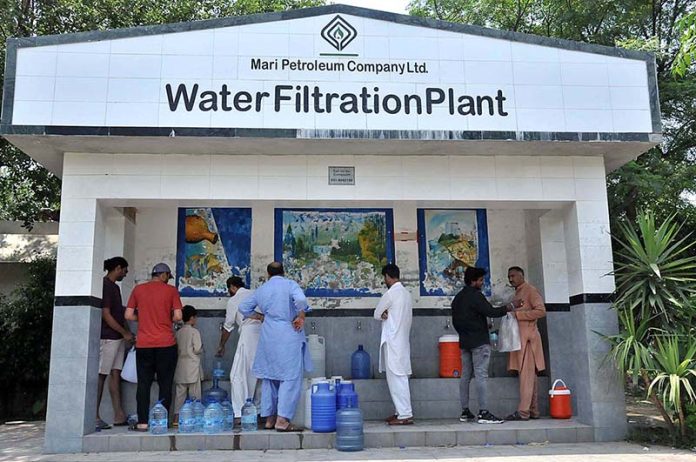 People fill their pots with clean drinking water from water filtration plant in I-8 Sector