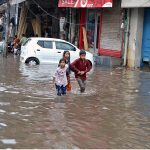 Children wading through water accumulated in Lakshmi Chowk due to heavy rain