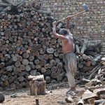 Labourer busy in cutting wood into pieces at his workplace