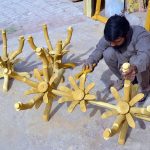 A wood worker given the final touches and polishes on a clothes hanger stand at Shahdara Furniture Market
