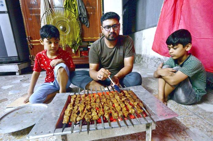 A boy preparing barbeque of meat on the occasion of 3rd day of Eid-ul-Azha at his home