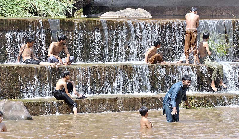 Youngsters jumping and bathing in the water channel of Rawal Dam to get some relief from hot weather in Federal Capital