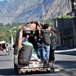People hanging on passenger van in risky way may cause any mishap, needs the attention of concern authorities.