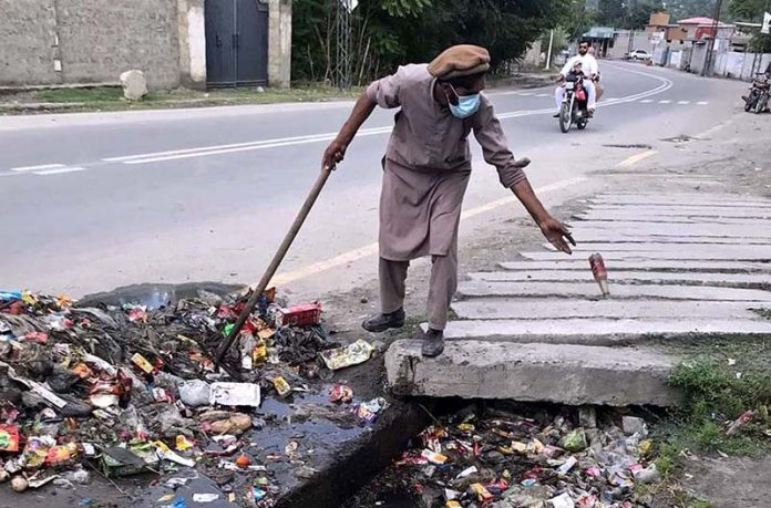 A worker busy in cleaning and pulling out garbage from Nullah