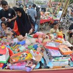 Women and children selecting and purchasing old toys at a roadside stall in Empress Market