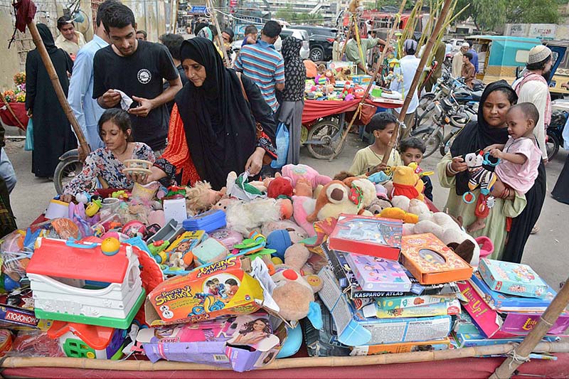 Women and children selecting and purchasing old toys at a roadside stall in Empress Market