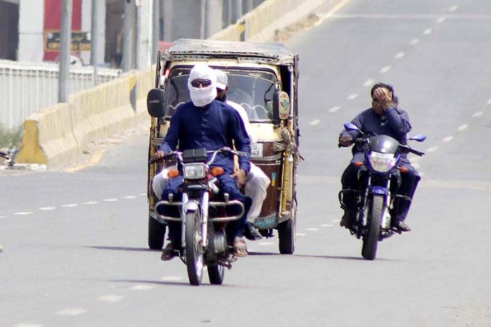 Motorcyclist on the way cover his face with piece of cloth to protect from direct sunlight during hot weather in the city