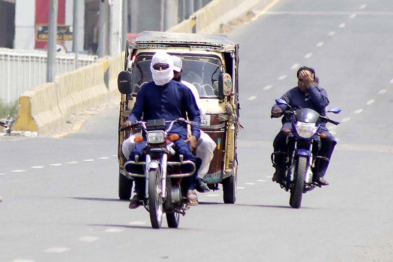 Motorcyclist on the way cover his face with piece of cloth to protect from direct sunlight during hot weather in the city